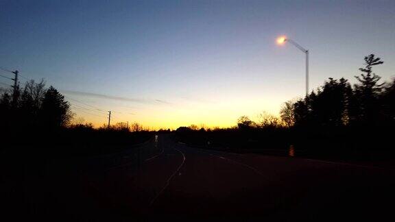 在日出时驾驶乡村道路清晨太阳从地平线升起时司机的视角