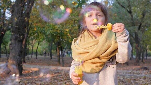 快乐的小女孩吹气泡和微笑在公园的背景树