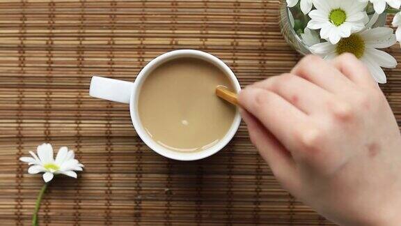 俯视图女手搅拌糖或牛奶在一杯热咖啡或茶