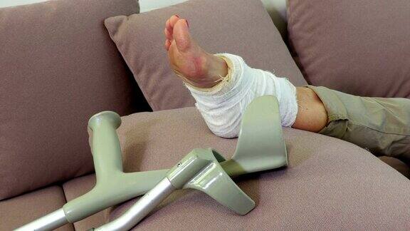 靠近沙发上女人受伤的腿和拐杖