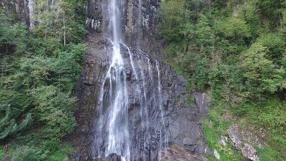 鸟瞰高瀑布水从高岩石在森林中流动