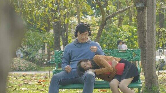 一对快乐的小情侣在公园的长椅上放松女孩倚在男友的大腿上看书