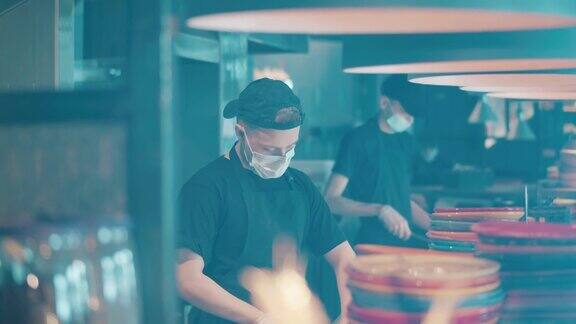 戴着口罩的厨师正在餐厅柜台后面工作