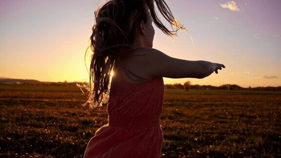 SLOMO快乐的女孩在草地在日落