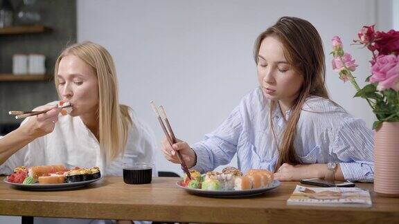 两个漂亮的女孩在家吃日本菜卷在盘子里是不一样的很好吃