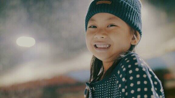 在雪地里看相机的亚洲小女孩的肖像