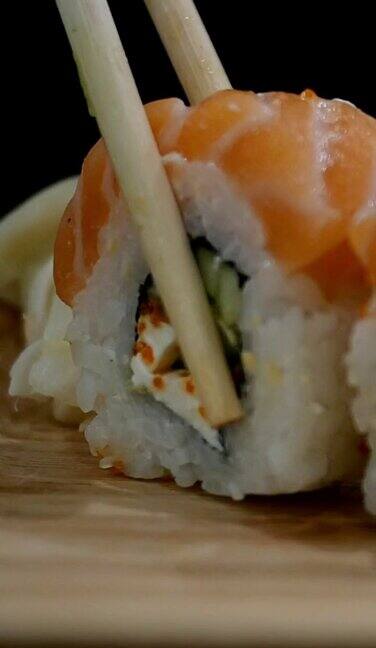 日本的食物用筷子从木板上拿起鲑鱼寿司卷