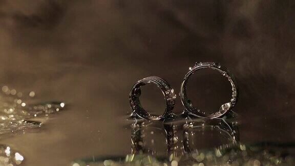 结婚戒指在暗色的水面上闪闪发光水滴近距离