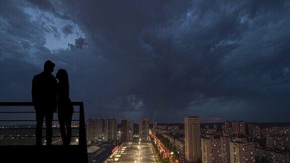 这对情侣站在阳台上以下雨的城市为背景hyperlapse