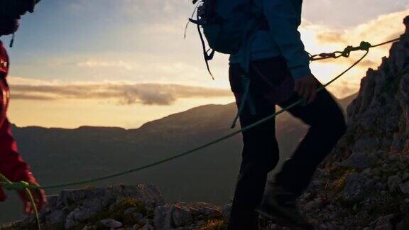 日出时三个登山家组成绳索队爬上山坡