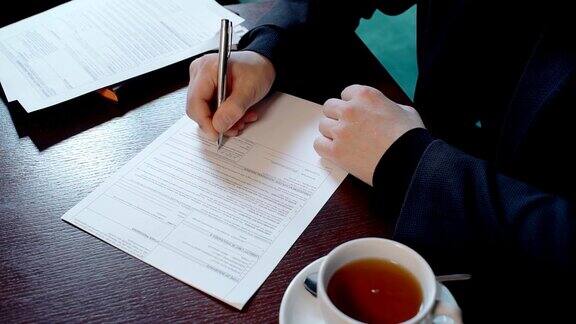 一个成功的商人正坐在餐厅的办公桌前签合同