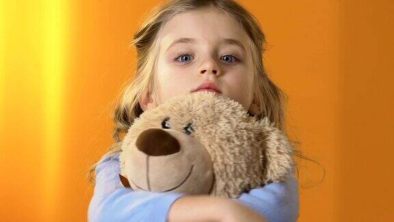 美丽悲伤的学龄前女孩抱着泰迪熊忍受着家庭问题
