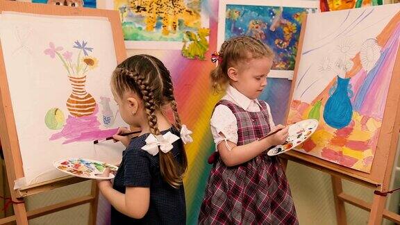两个小女孩站在画架前画画