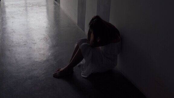 孤独的年轻女性感到沮丧和压力坐在黑暗的走道消极的情绪和心理健康
