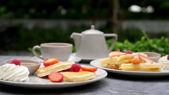 草莓煎饼鲜奶油和蜂蜜带茶壶的杯子