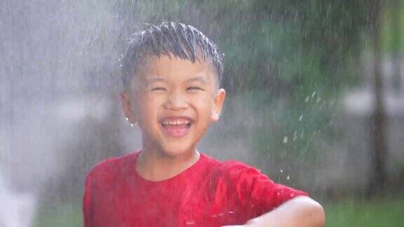 穿着靴子的亚洲孩子在公园玩溅水和泥夏天和快乐