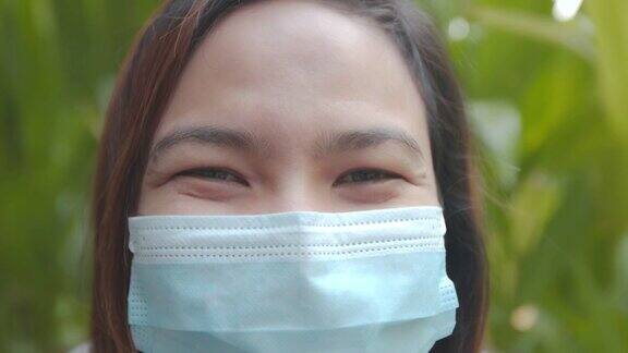 在新冠肺炎大流行期间一名亚洲妇女坐在咖啡馆里戴着面具微笑