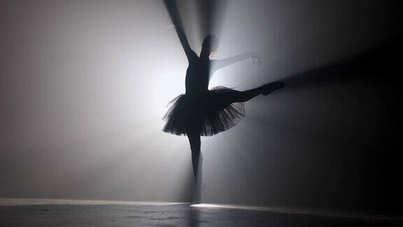职业芭蕾舞演员在聚光灯下跳芭蕾舞大舞台上烟雾缭绕漂亮的年轻女孩穿着黑色芭蕾舞裙在泛光灯的背景黑色和白色4k