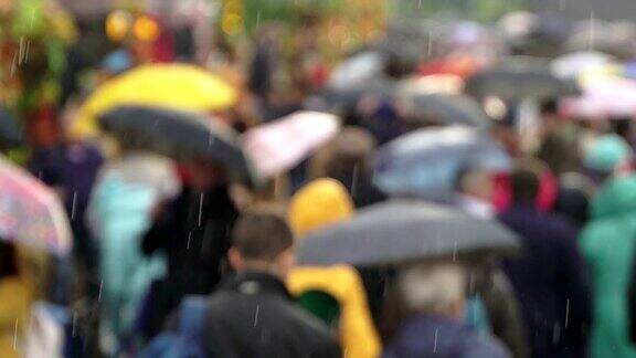 人们在繁忙的商业街撑着雨伞挡雨真正的时间黄色雨伞和黄色雨衣人们在雨中带着雨伞上下班模糊的散景城市阴雨天的自然背景