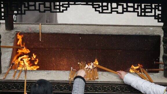 慢镜头火和香烟在中国传统寺庙祈祷者把燃烧的香放入香炉4K视频