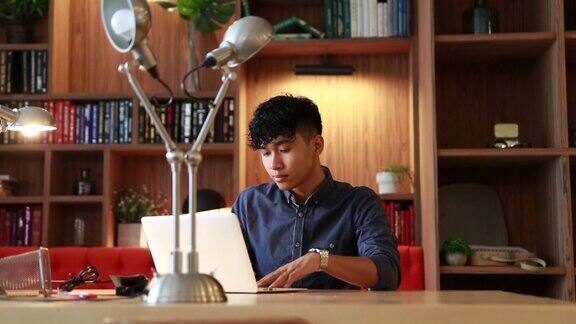 年轻的亚洲人正在图书馆用笔记本电脑工作