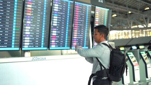 带防护口罩的旅客在机场候机楼检查航班时刻表
