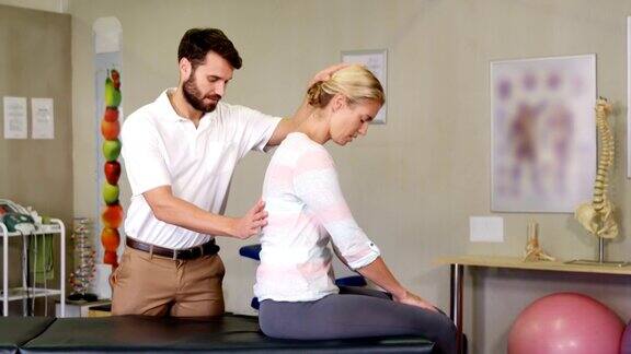 男性理疗师给女性病人做背部按摩