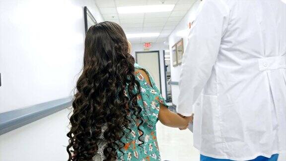 医生带着小女孩走过医院的走廊