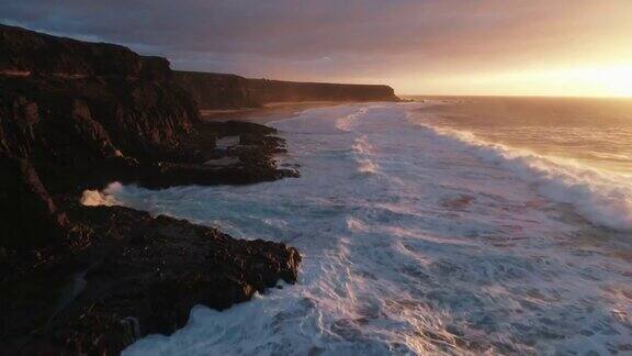 无人机拍摄的日落时海浪撞击岩石的画面