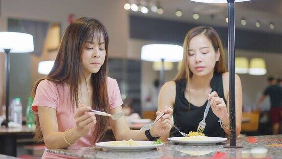 亚洲年轻的朋友美女一起在餐厅吃饭他们愉快地聊天快乐地吃着食物在自助餐厅的年轻人聚会