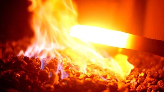 一个铁匠锻造一把剑在他的车间在他的熔炉内燃烧的煤炭和火焰在慢动作