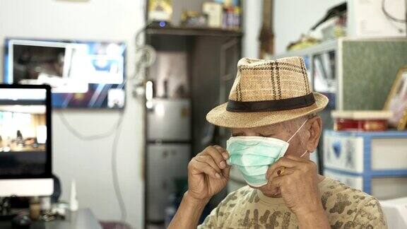 亚洲老人戴着口罩在家保护新冠肺炎的场景