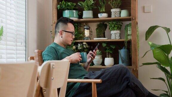 一位中年男子在家里喝着咖啡一边看手机