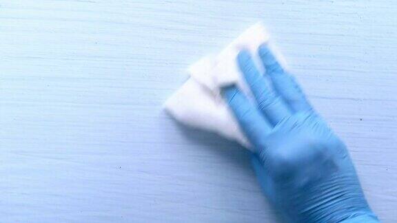 手戴蓝色橡胶手套用布清洁桌子