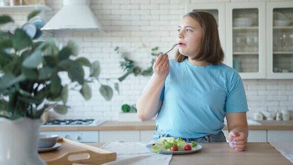 大号女人坐在木桌旁吃蔬菜沙拉