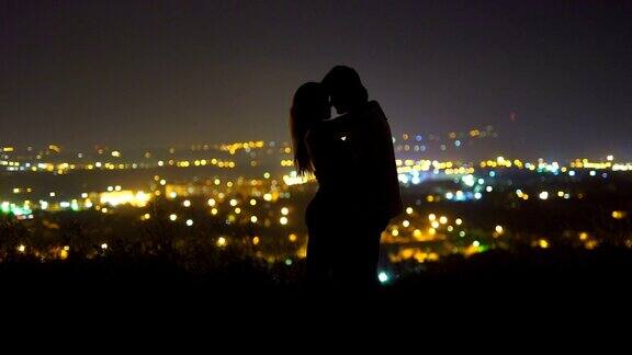 这对情侣以城市的灯光为背景接吻晚上的时间