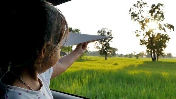 可爱的小女孩在乡下玩着玩具纸飞机窗外晚上放松的活动概念Slowmotion拍摄