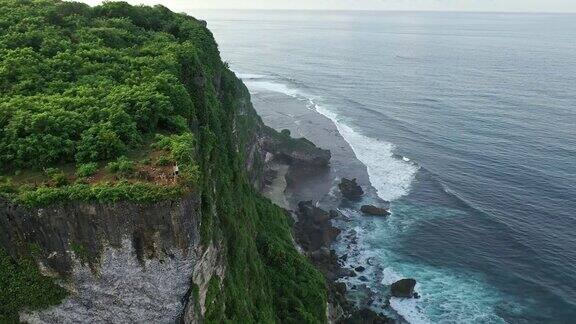 女人站在悬崖上看海边的鸟瞰图巴厘岛乌鲁瓦图