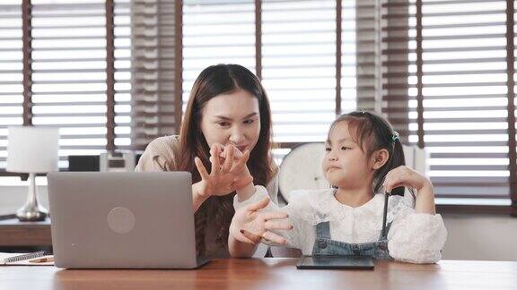亚洲母亲教女儿做家庭作业计算数字数学后从学校回家母亲使用笔记本电脑数字技术工作