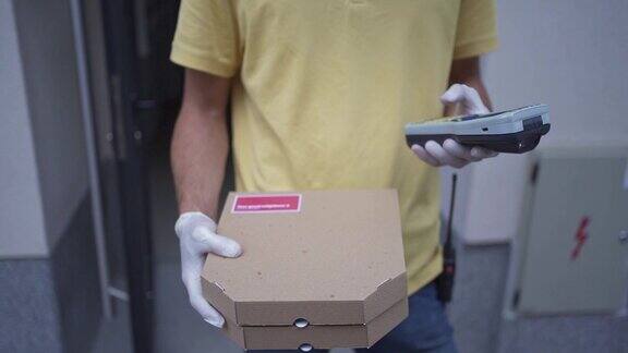 披萨送餐员拿着两个披萨盒在条形码阅读器上输入信息