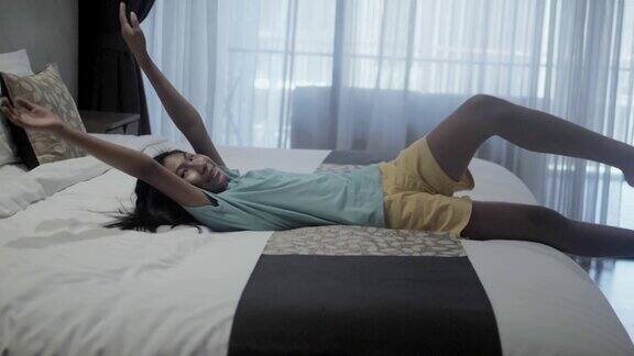 微笑的亚洲女孩躺在酒店的床上度假生活理念