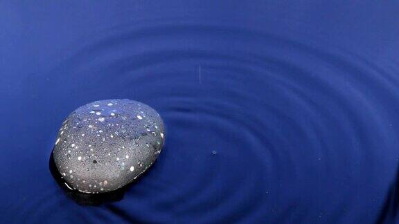 落一滴水在黑色的石头和蓝色的水