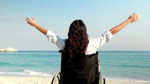 在海滩上伸开双臂的残疾妇女