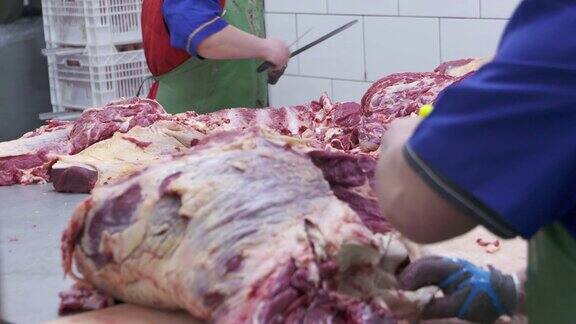 在肉类和香肠制造工厂正在切牛肉胴体的屠夫正在切生肉