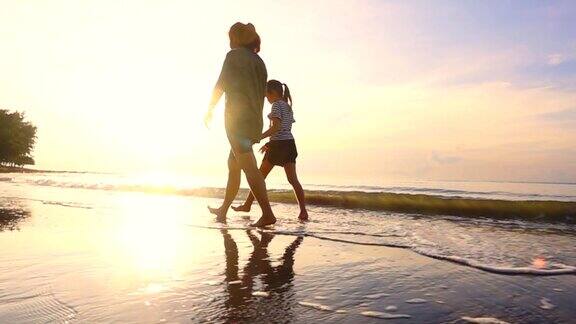 高清慢镜头:一家人在日落时分的热带海滩上散步