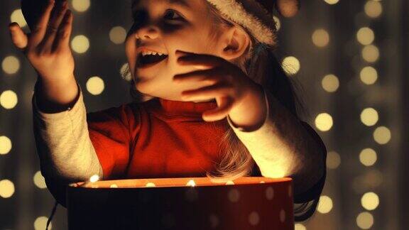小女孩打开了一个发光的礼物盒发现了一个闪闪发光的圣诞装饰品