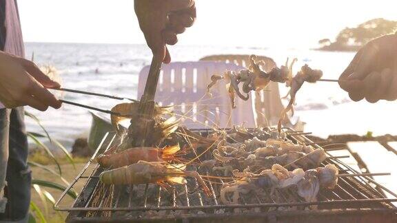 一群朋友在海滩上烧烤猪肉、虾和海鲜聚会活动