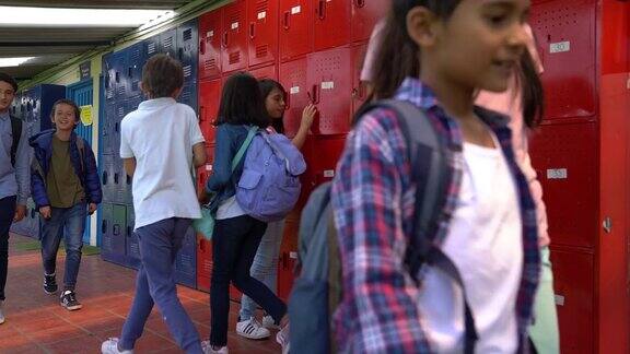 中学学生走在储物柜前而女学生正在把她的笔记本放在储物柜里