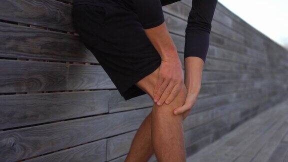 膝盖疼痛的人在户外跑步时膝盖或关节受伤男人按摩他的膝盖以减轻疼痛