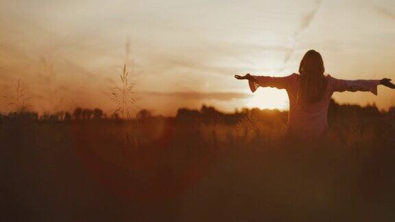 日落时分一名年轻女子漫步在田野中央呼吸着新鲜空气